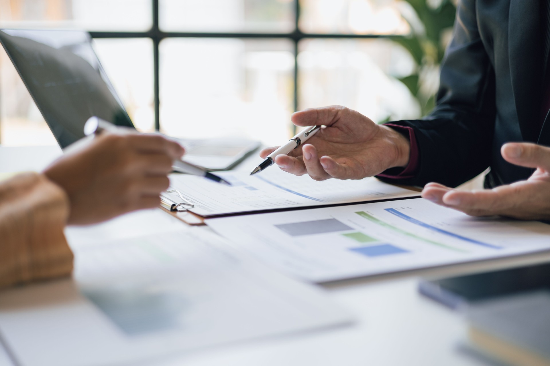Business executives meeting with financial advisors are analyzing company financial reports and planning new business project investments.
